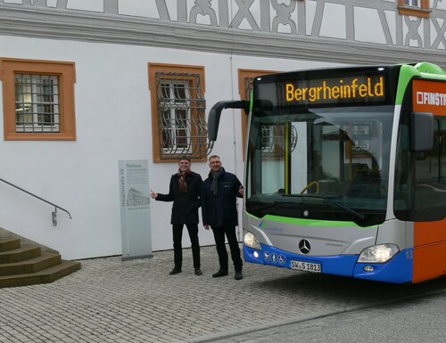 Bürgermeister Ulrich Werner und Harald Mendrok von den Stadtwerken Schweinfurt stehen zwischen Rathaus und einem Stadtbus und freuen sich über die künftige Zusammenarbeit